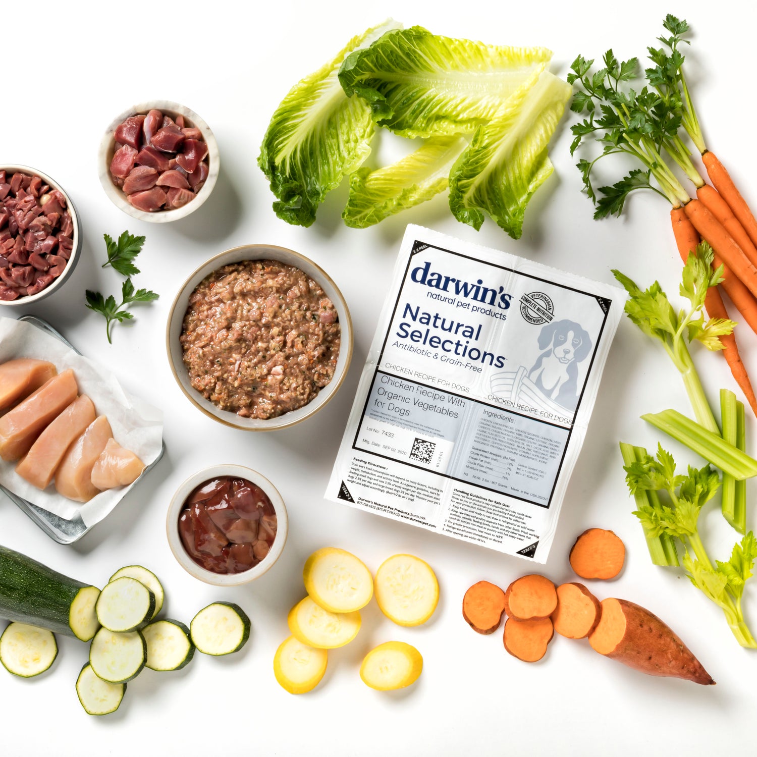 Darwin's raw pet food is displayed in its packaging and in a bowl, surrounded by fresh ingredients used in the raw food for dogs and cats.